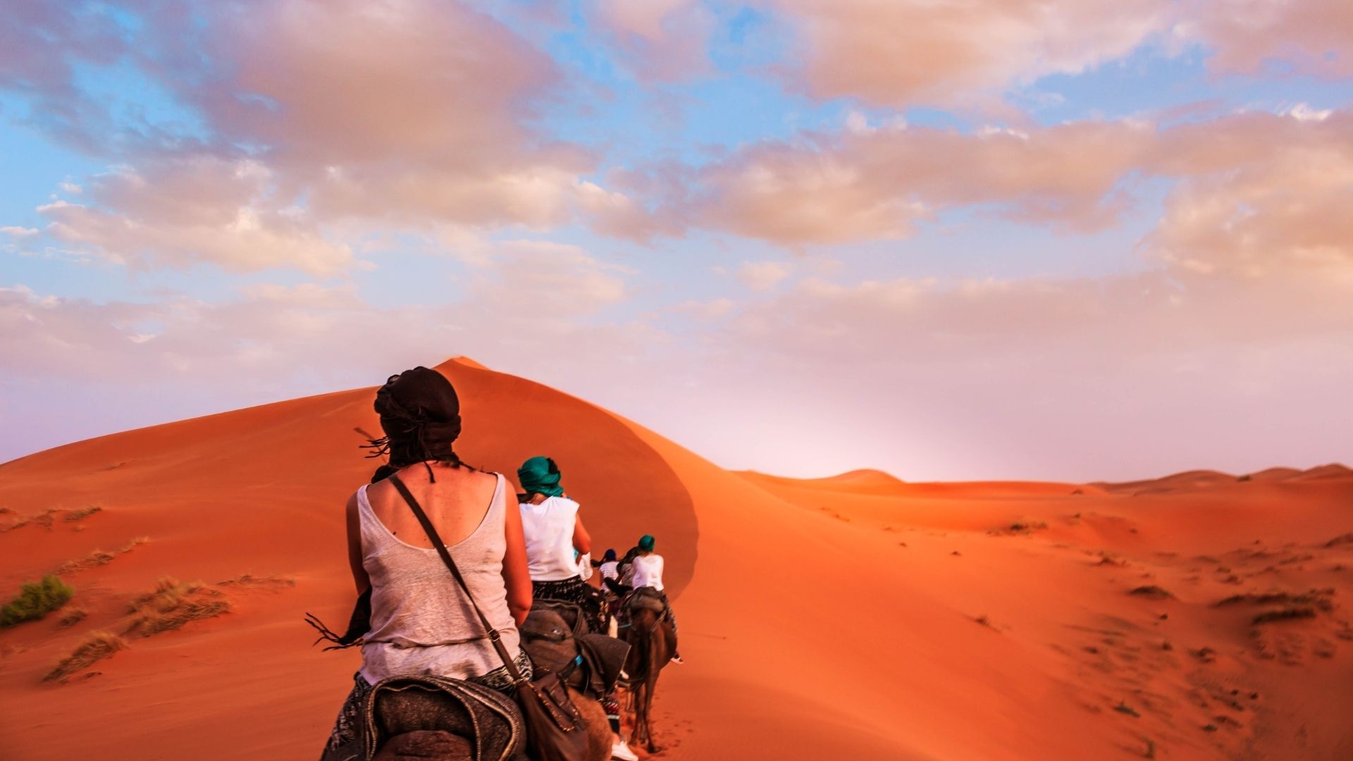 Due viaggiatori davanti alla grande duna al tramonto — offerte viaggi marocco